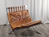 a brown leather chair that is sitting on a wooden floor
