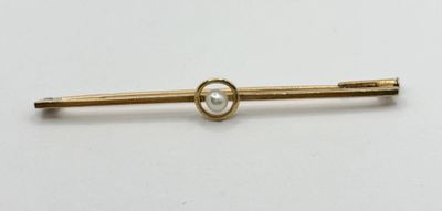 un gros plan d'une broche en or ornée d'une perle