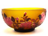 a yellow bowl with pink flowers on it on a white surface