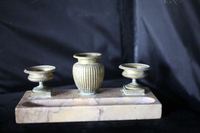 trois vases posés sur un socle en marbre, sur fond noir
