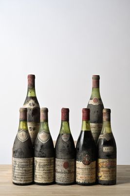 six bottles of wine are lined up on a wooden table