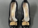 pair of black shoes with gold buckles on them on a gray surface