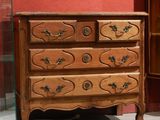 une commode en bois dans une pièce où est accrochée une horloge au mur