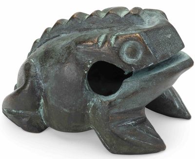 une petite grenouille en bronze posée sur une surface blanche