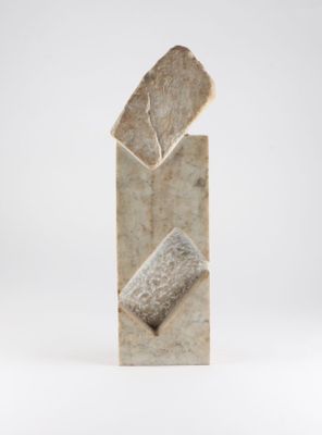 sculpture représentant un bloc de pierre surmonté d'une feuille, posée sur une surface blanche