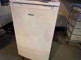 a small white refrigerator in the middle of a kitchen