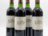 four bottles of wine are lined up on a white surface