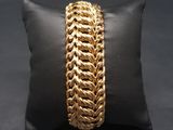un oreiller noir sur lequel repose un bracelet à chaîne dorée