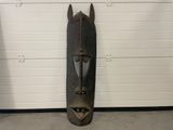 un masque en bois accroché au mur d'un garage