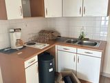 a kitchen with a sink, stove, cabinets, and a trash can