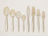 five forks, a spoon, and a knife on a white surface