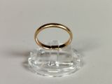 a gold ring on a clear stand on a white surface