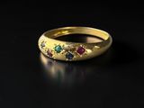 gros plan d'une bague en or avec des pierres multicolores