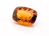 a close up of a yellow sapphire stone on a white surface