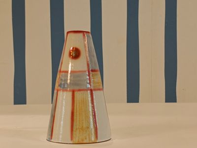 a vase that is sitting on a table in front of a striped wall