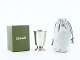 a silver cup next to a green box on a white surface