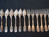 a lot of silver spoons and forks on a black table