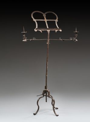 une girouette en métal à l'ancienne, composée de trois bougies posées sur un socle
