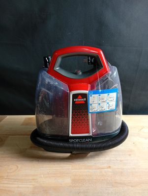 un aspirateur rouge et noir posé sur une table en bois