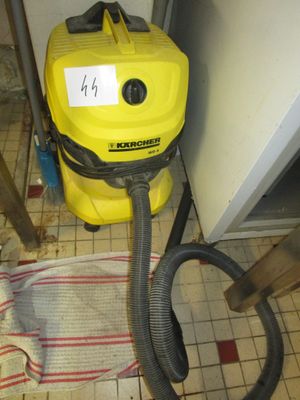 un aspirateur jaune et noir posé sur un sol carrelé