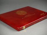 an open red book sitting on top of a table next to a gray table