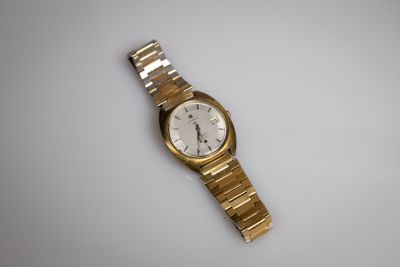 une image d'une montre-bracelet en or sur une surface blanche