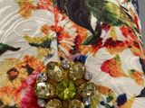 a close up of a flowered hat with a brooch on it