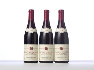 three bottles of red wine are lined up on a table