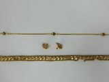 two gold bracelets and a gold necklace on a white surface