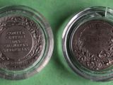 two silver coins in a glass container on a green surface