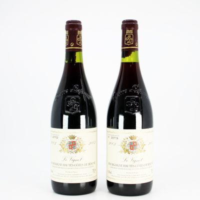 two bottles of red wine sitting next to each other on a white surface