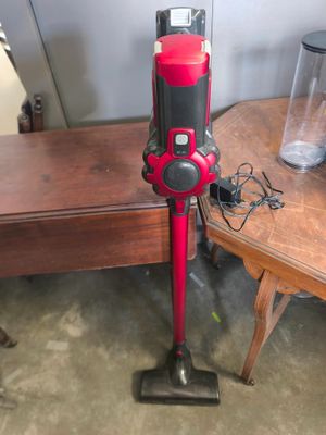 un aspirateur rouge et noir posé sur une table en bois