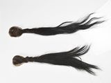 deux mèches de cheveux noirs sont posées sur une surface blanche