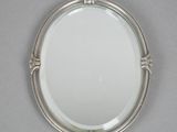 an image of a mirror with a silver frame on a gray surface