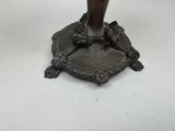 a bronze vase on a stand on a white surface