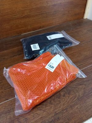 deux sacs contenant des vêtements orange et noirs, posés sur un plancher en bois