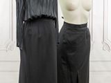 two mannequins in front of a white wall and a black dress on a mannequin stand