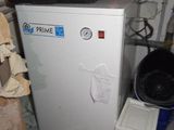 a small white refrigerator in a room with a lot of clutter