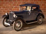 a vintage car that is parked in front of a brick wall