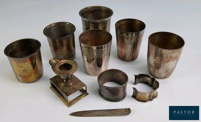 de nombreuses tasses en argent et un couteau posés sur une table