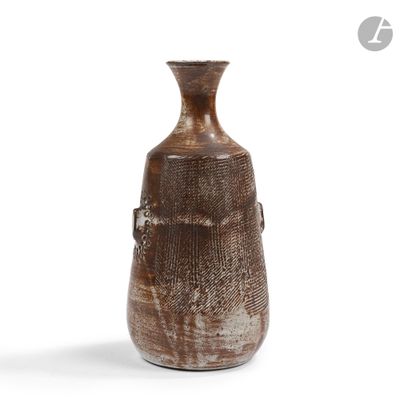 un vase brun posé sur une surface blanche