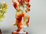 two figurines of a woman holding flowers on a stand