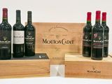 trois bouteilles de vin rouge dans un coffret en bois posé sur une surface blanche