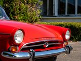 a red classic car parked in front of a house