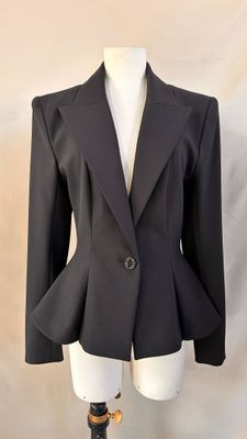 the jacket is black and has a gold buckle on the front