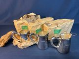 three silver coffee pots and two silver mugs on a blue background