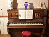un piano dans un coin de la pièce, avec un tabouret rouge