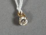 un gros plan d'un pendentif en diamant suspendu à un cordon, posé sur une surface grise