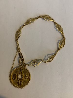 Gros plan sur un bracelet en or orné d'une pièce de monnaie