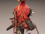 une image représentant une sculpture d'une femme vêtue d'une robe rouge et portant une coiffe